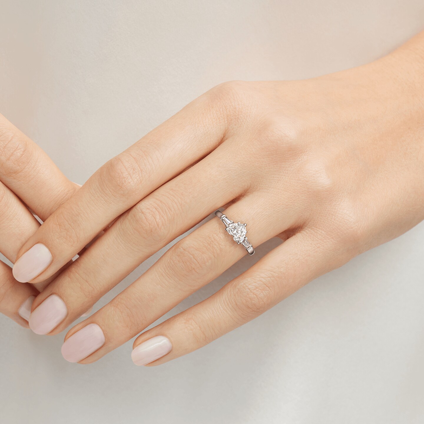 Bague de fiançailles Classic Winston en diamant taille coeur et diamant latéraux taille baguette présentée sur un modèle 