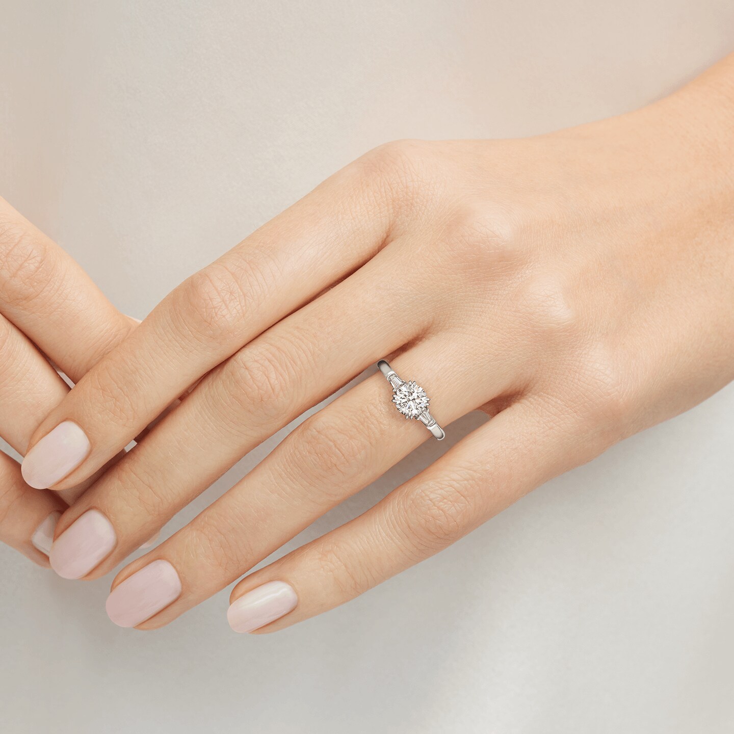 Bague de fiançailles Classic Winston diamant taille brillant et diamants latéraux taille baguette présentée sur un modèle 